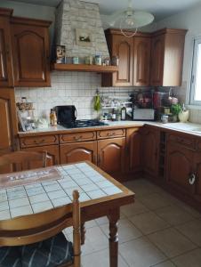 a kitchen with wooden cabinets and a table in it at Le jardin aux oiseaux in Saint-Jouan-de-lʼIsle