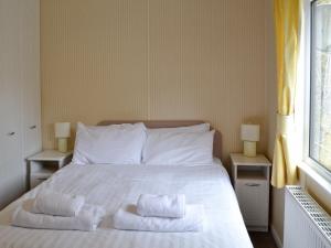 a bedroom with a white bed with towels on it at Hollys Lodge - E4072 in Brough