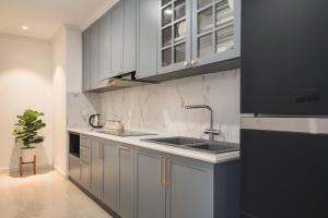 une cuisine avec des armoires grises et un évier dans l'établissement Troy House - Vinhomes Dcapitale - Cau Giay, à Hanoï