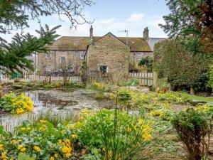 una casa antigua con un jardín delante de ella en Old Brewery Cottage- Uk3002, en Haltwhistle