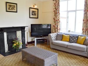 a living room with a couch and a tv at Somersal Farmhouse in Somersal Herbert