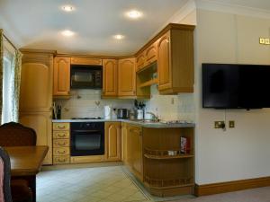 a kitchen with wooden cabinets and a tv on the wall at Leatheswater in Thirlmere