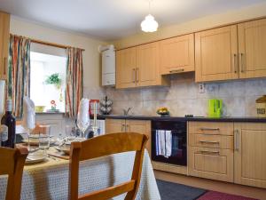 a kitchen with wooden cabinets and a table with a table cloth at Caroch Cottage in Comrie