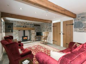 a living room with a red couch and a fireplace at Waterfall Wood Cottage in Patterdale
