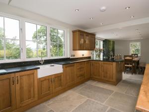 een keuken met houten kasten en een witte wastafel bij Waterfall Wood Cottage in Patterdale