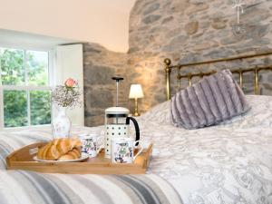 een dienblad met croissants en een bord brood op een bed bij Waterfall Wood Cottage in Patterdale