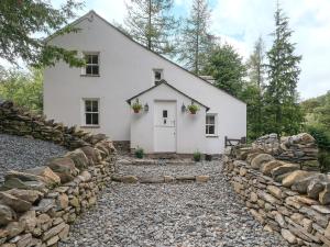 een wit huis met een stenen muur bij Waterfall Wood Cottage in Patterdale
