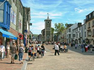 a crowd of people walking down a street with a clock tower at 15 Elm Court in Keswick