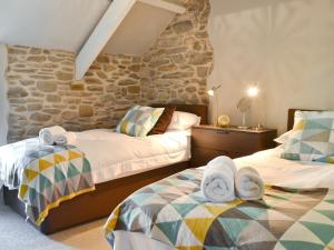 a bedroom with two beds and a stone wall at Ivy Bush Cottage in Llanddewi-Brefi