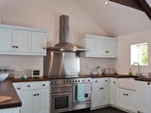 a kitchen with white cabinets and a stove top oven at Llangrannog in Llandyssiliogogo
