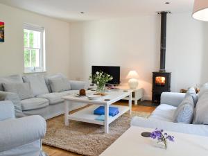 a living room with white furniture and a fireplace at Llangrannog in Llandyssiliogogo