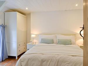 a white bedroom with a large bed and a cabinet at Llangrannog in Llandyssiliogogo