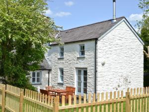 a white cottage with a wooden fence in front of it at Llangrannog in Llandyssiliogogo