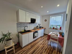 a kitchen with white cabinets and a wooden floor at Apartament 5 minut od Parku Zamkowego in Pszczyna +18 photos