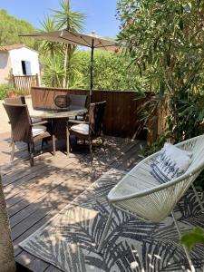 een terras met een tafel, stoelen en een parasol bij Gite 525 avec piscine in Sainte-Maxime