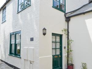 ein weißes Backsteinhaus mit grünen Fenstern und einer grünen Tür in der Unterkunft Tennay Cottage in Wareham