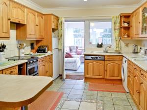 a kitchen with wooden cabinets and a large window at South Cleeve Bungalow in Otterford