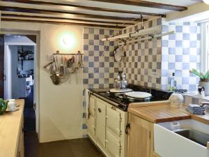 a kitchen with blue and white tiles on the wall at Birkerthwaite Farmhouse in Eskdale