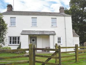 a white house with a wooden fence in front of it at Birkerthwaite Farmhouse in Eskdale