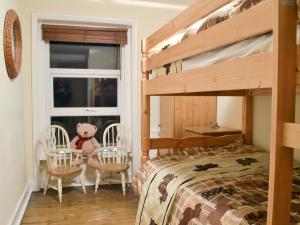 een slaapkamer met een stapelbed en stoelen met een teddybeer bij Chestney House in Hunstanton