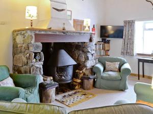sala de estar con chimenea de piedra y 2 sillas en Tigh Na Caoiraich en Tomdoun