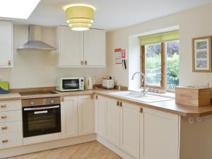 a kitchen with white cabinets and a sink and a microwave at Garden Cottage in Bridlington