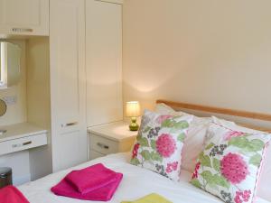 a bedroom with a bed with pink and white pillows at Garden Cottage in Bridlington