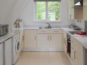 cocina blanca con fregadero y lavavajillas en Hives - W43108, en Bradworthy