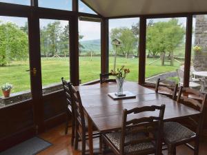 a dining room with a table and chairs and windows at Blackhill Gate Cottage in Taxal