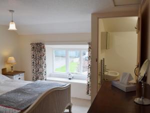 a bedroom with a bed and a window and a tub at Blackhill Gate Cottage in Taxal