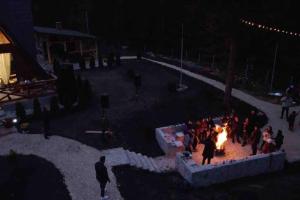 a group of people standing around a fire at night at Campulung Chalet A Frame in Câmpulung