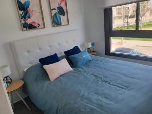 ein Schlafzimmer mit einem großen Bett mit blauer Bettwäsche und einem Fenster in der Unterkunft Casa LeLa met dakterras in Pilar de la Horadada