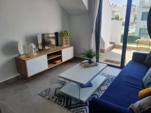 ein Wohnzimmer mit einem blauen Sofa und einem TV in der Unterkunft Casa LeLa met dakterras in Pilar de la Horadada