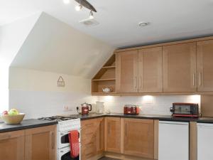 a kitchen with wooden cabinets and a white stove top oven at Sandhaven in Culross