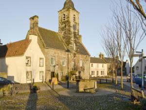 un vieux bâtiment avec une tour d'horloge dans une rue dans l'établissement Sandhaven, à Culross