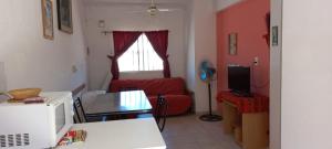 a living room with a red couch and a microwave at Complejo Veleta de Mar in Las Grutas