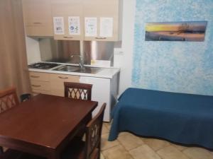 een kleine keuken met een tafel, een wastafel en een bed bij B&B Acquamarina Villasimius in Villasimius