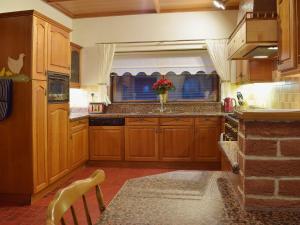 a kitchen with wooden cabinets and a vase of flowers at Maes Y Wawr in Trostre