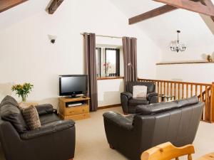 - un salon avec 2 fauteuils en cuir et une télévision dans l'établissement Curlew Cottage, à Great Blencow