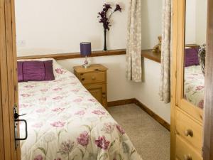 - une chambre avec un lit et une table avec une lampe dans l'établissement Curlew Cottage, à Great Blencow