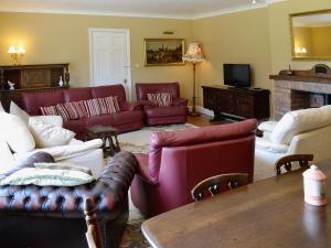 a living room with red couches and a fireplace at Conifers in South Molton