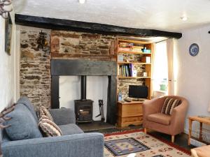 a living room with a fireplace and a couch and chair at Blease Cottage in Threlkeld