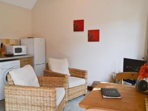 a living room with wicker chairs and a white refrigerator at Thyme - E4485 in Ludham