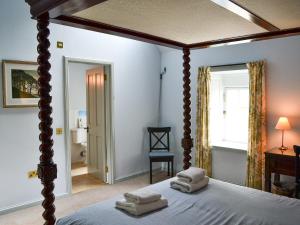 a bedroom with a canopy bed with towels on it at Courtyard Cottage in Smailholm