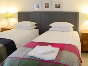two beds in a hotel room with towels on the bed at The Byre in Rispond
