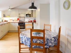 uma cozinha com uma mesa e cadeiras e uma cozinha com uma mesa e uma mesa em The Byre em Rispond