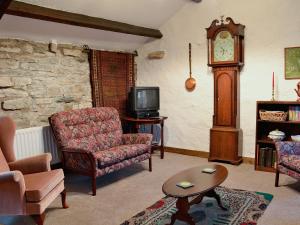 a living room with a grandfather clock and a chair at Cranesbill Barn in Ravenstonedale