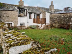 a stone wall in front of a house at Cranesbill Barn in Ravenstonedale