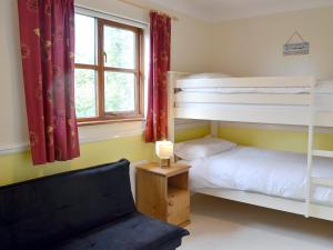a bedroom with two bunk beds and a chair at Birchwood in Marhamchurch