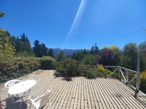 una terraza de madera con mesa y sillas. en Chacra La alborada en El Bolsón